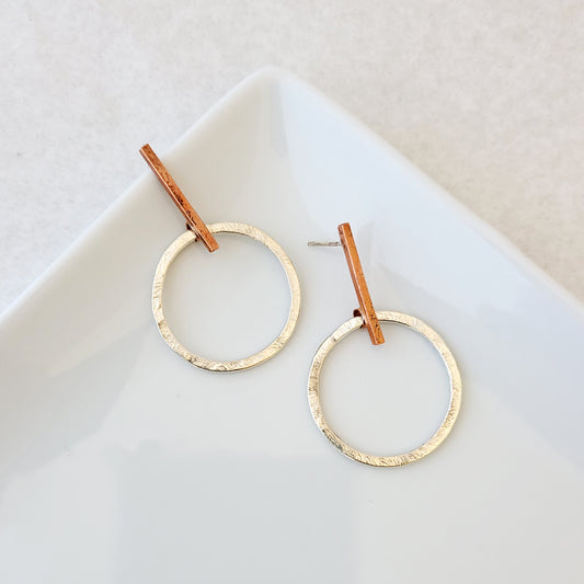 Hand-fabricated post earrings of sterling silver circles hanging from copper bar, both with a bolder gauge, square form.