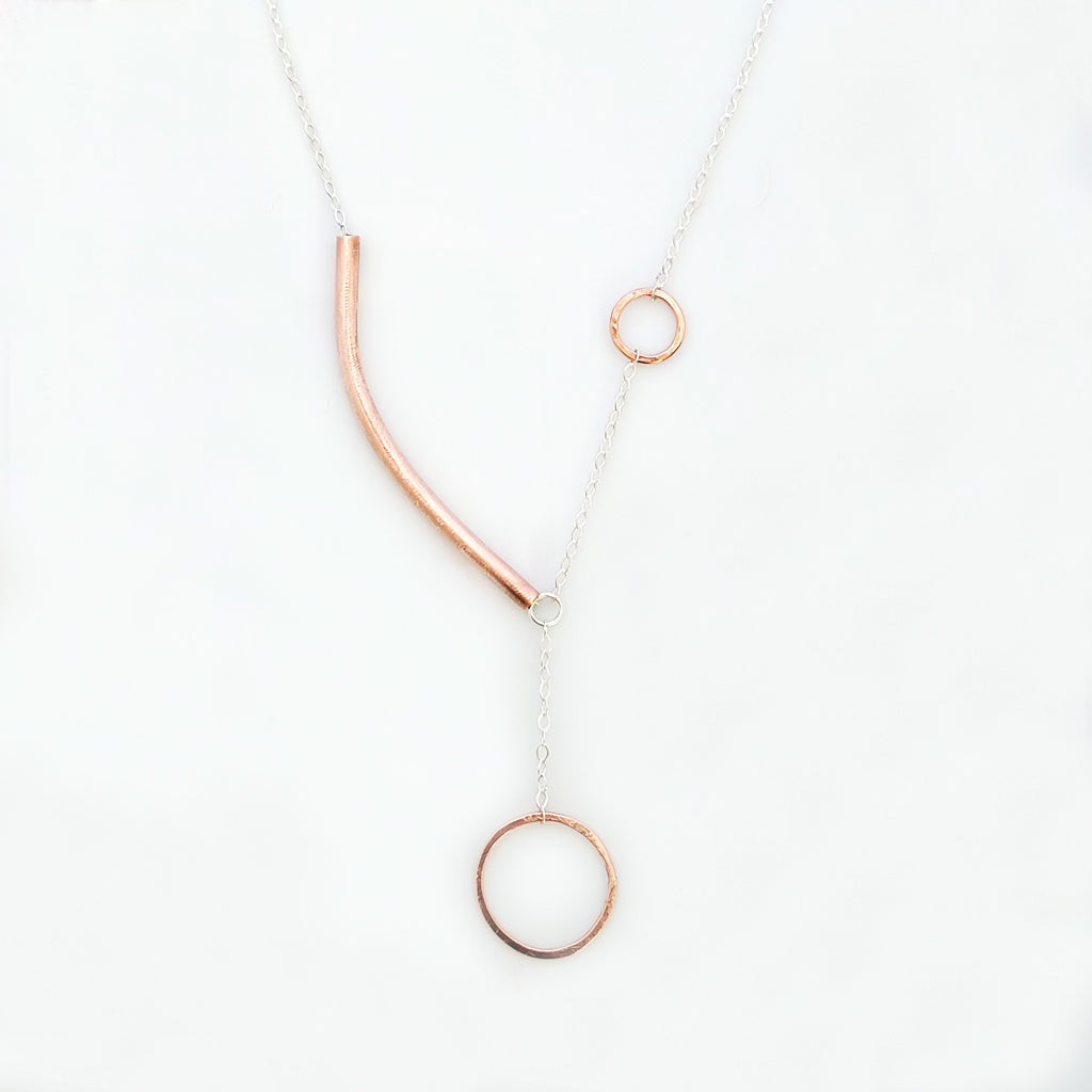 Handmade necklace.  Hand-formed copper circles connected with sterling chain, offset with asymmetric copper tube arc