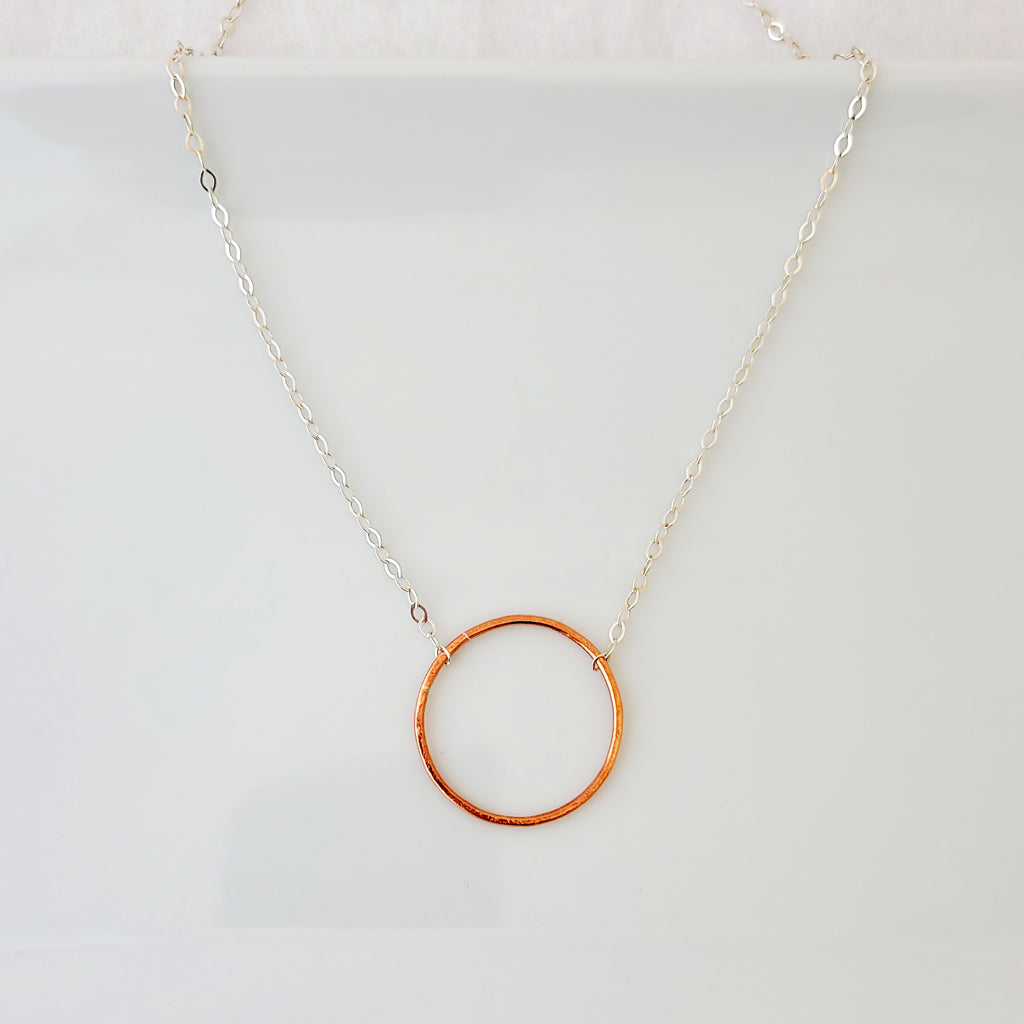 Hand-fabricated necklace with delicate copper circle connected with sterling silver chain