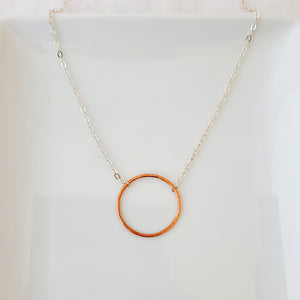 Hand-fabricated necklace with delicate copper circle connected with sterling silver chain