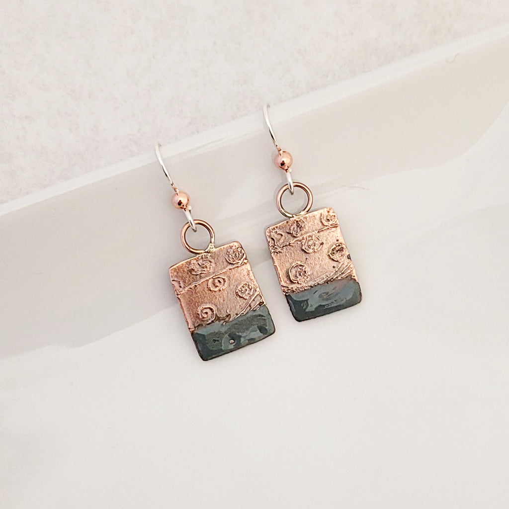 Handmade earrings.  Hand-fabricated copper rectangle, etched with swirl design, bottom with blue-gray enamel work
