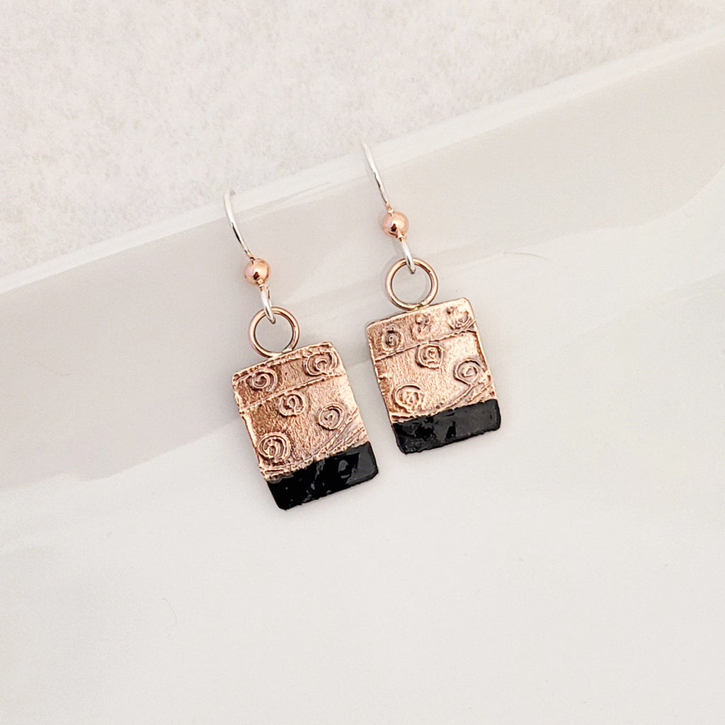 Handmade earrings.  Hand-fabricated copper rectangle, etched with swirl design, bottom with dark navy enamel work