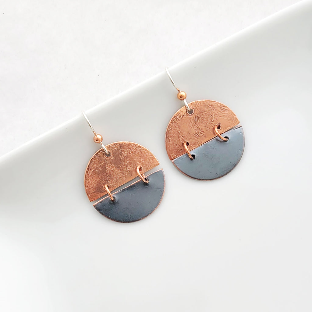 Handmade earrings of copper split circles with patina charcoal on bottom, connected with copper hoops