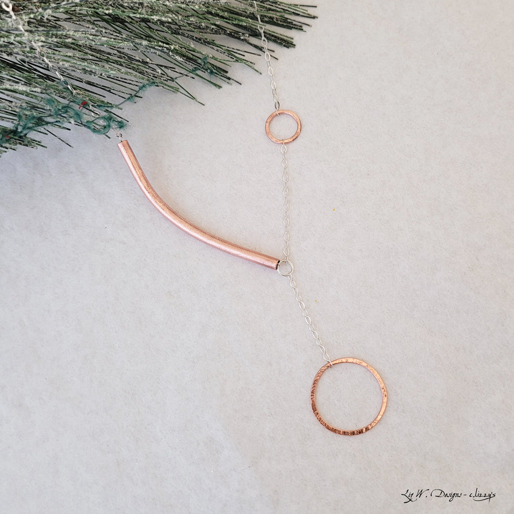 Handmade necklace.  Hand-formed copper circles connected with sterling chain, offset with asymmetric copper tube arc