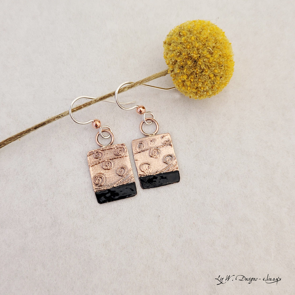 Handmade earrings. Hand-fabricated copper rectangle, etched with swirl design, bottom with dark navy enamel work