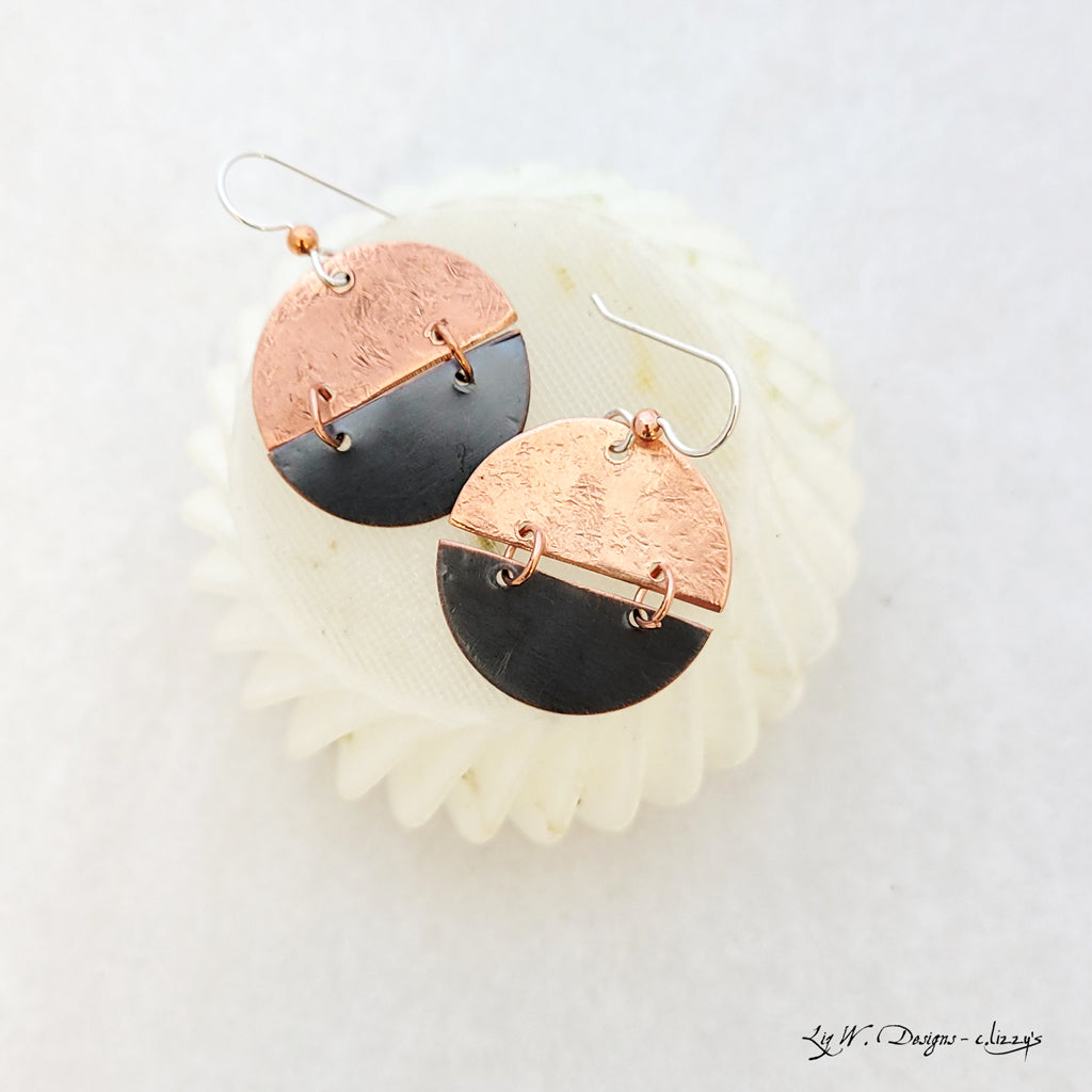 Handmade earrings of copper split circles with patina charcoal on bottom, connected with copper hoops