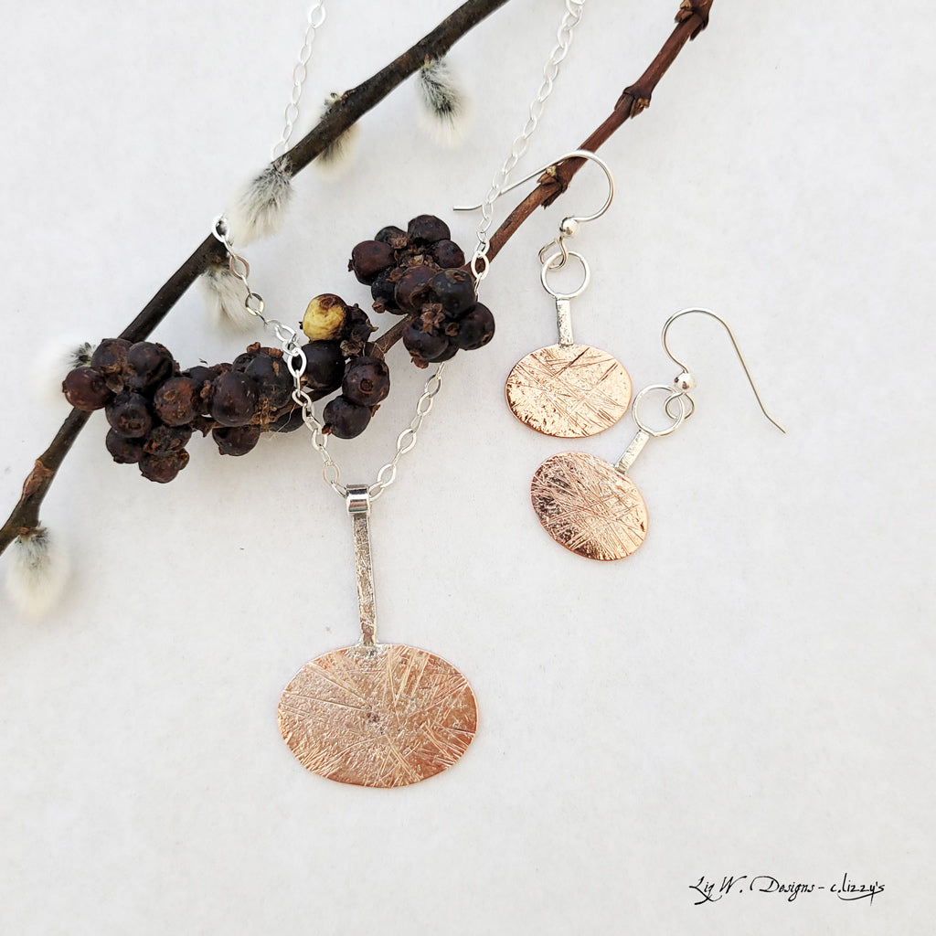 Handmade earrings of sterling silver layers over copper on side oval shape from sterling bar.