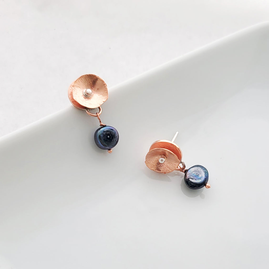 Hand-formed earring with textured copper flower with sterling silver center and darker freshwater pearl drop.