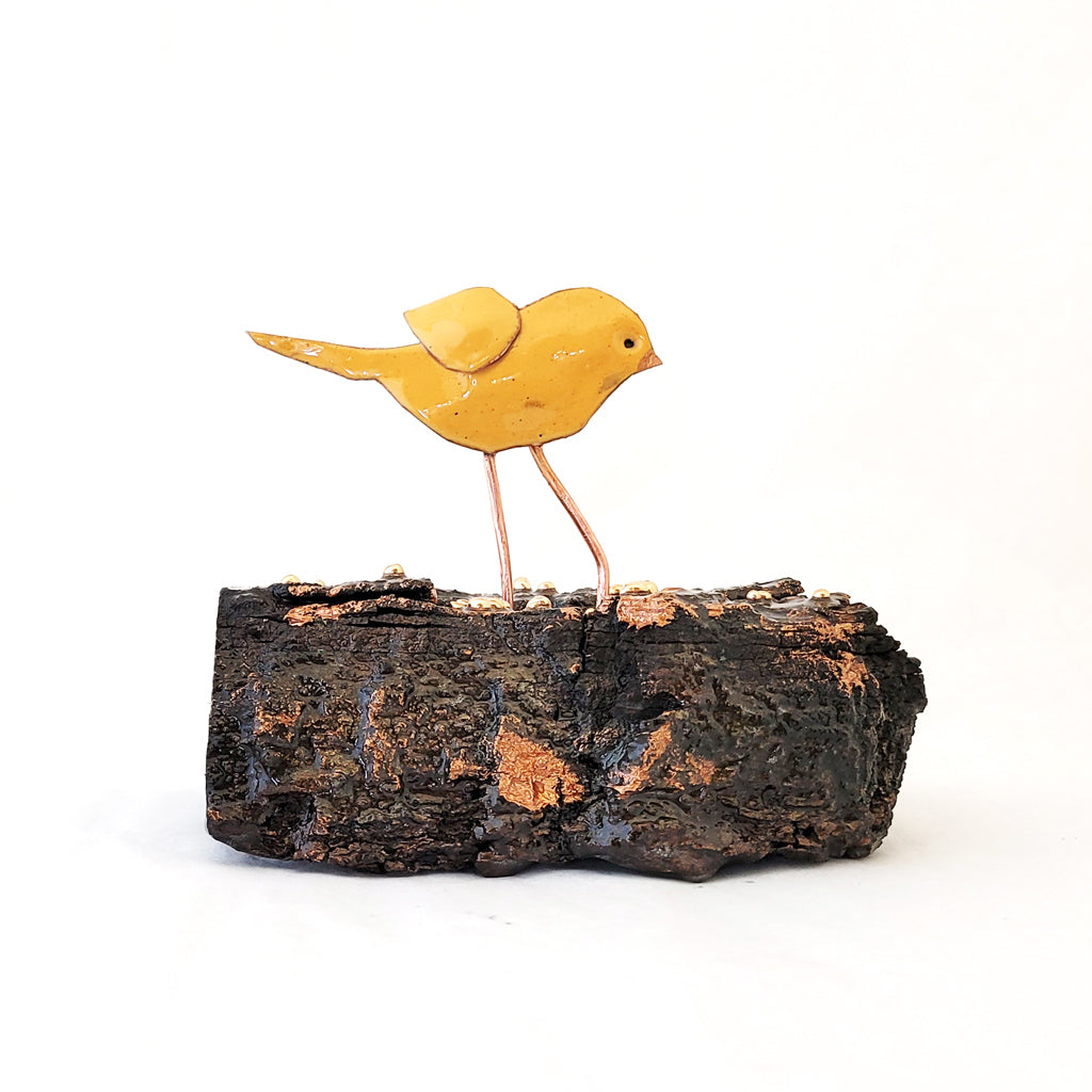 Hand-fabricated copper birdie with yellow enamel on cottonwood bark.