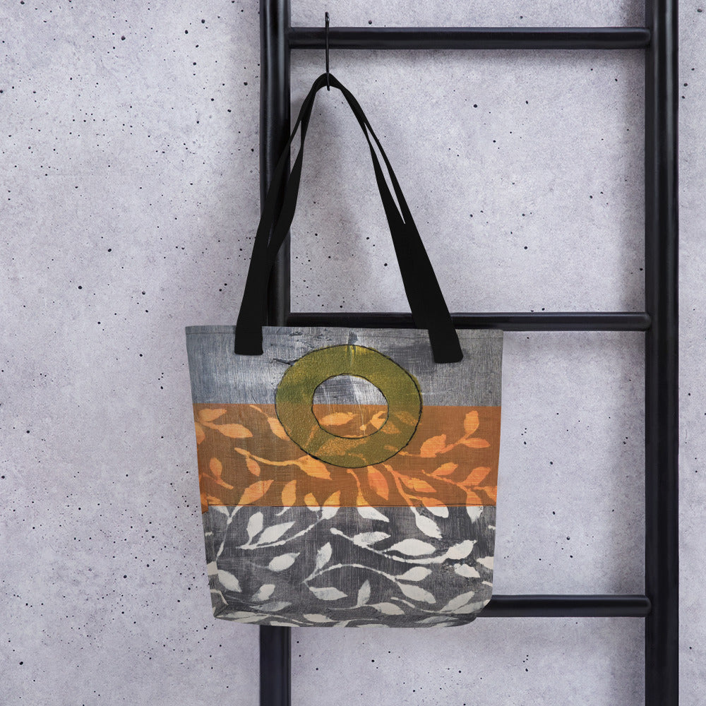 Tote bag of original art.  Avocado green circle on gray and light burnt orange background with off-white leaf design.