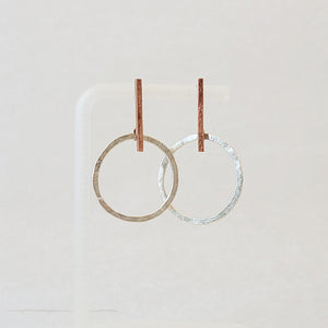Hand-fabricated post earrings of sterling silver circles hanging from copper bar, both with a bolder gauge, square form.